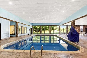 An indoor swimming pool with clear glass walls, a stone-tiled floor, and a view of the outdoors. - Comfort Inn Grantsville-Deep Creek Lake (Grantsville)