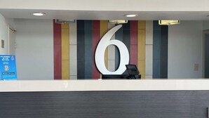 Ein Empfangsschalter mit einem großen Schild mit der Nummer 6, einem digitalen Telefon und einer Schautafel, die Mitgliedsbeiträge bewirbt.