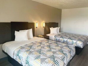Une chambre d’hôtel avec deux lits, chacun agrémenté d’une couvre-lit à motifs, d’une tête de lit en bois et d’une table de chevet avec une lampe et un téléphone.