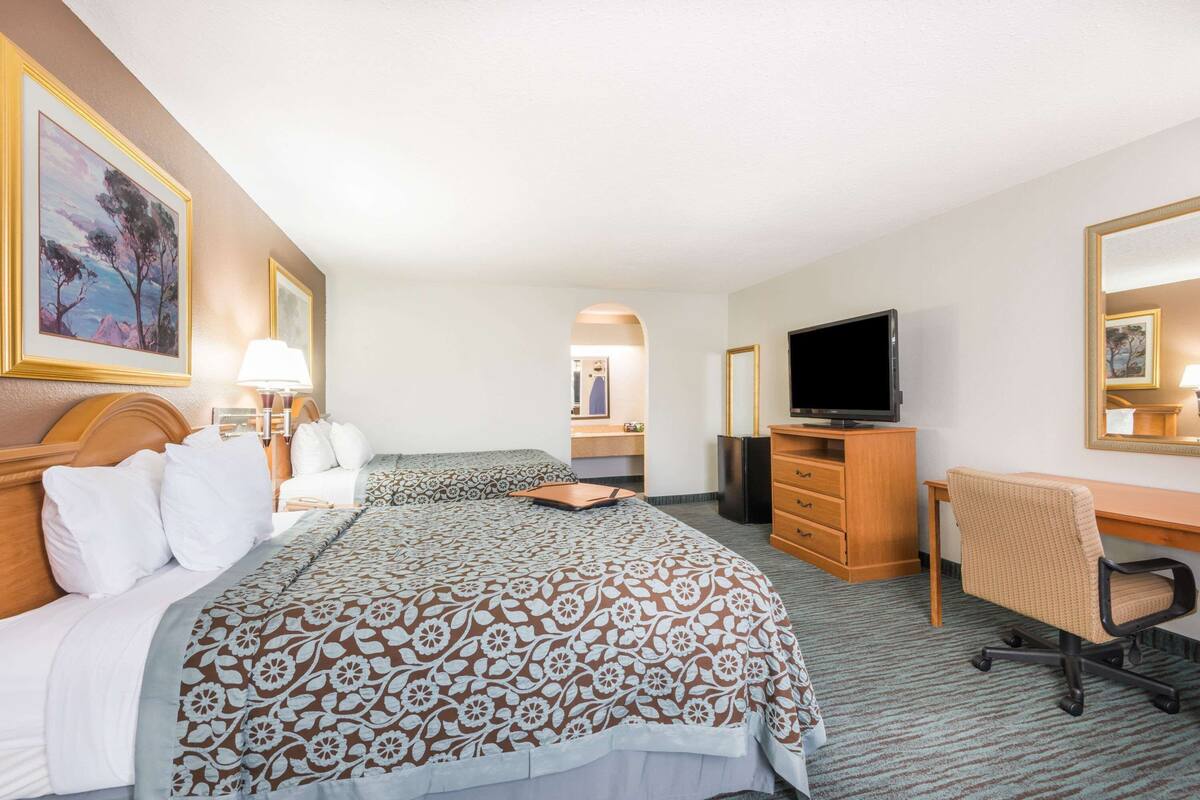 A hotel room with a bed, a desk, a television, and a mirror.