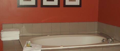 A bathroom with a bathtub, a towel, and three framed pictures on the wall.