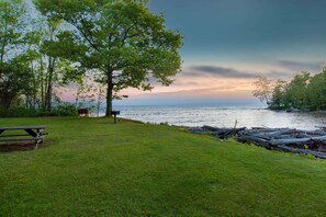 Enjoy a serene lakeside retreat with a grassy area, picnic table, and benches, perfect for dining or leisure.
