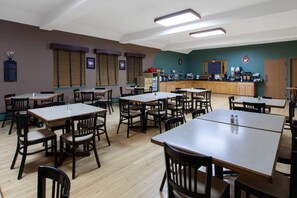 Enjoy meals in a spacious dining area with tables and chairs, a coffee station, and ample natural ambiance.
