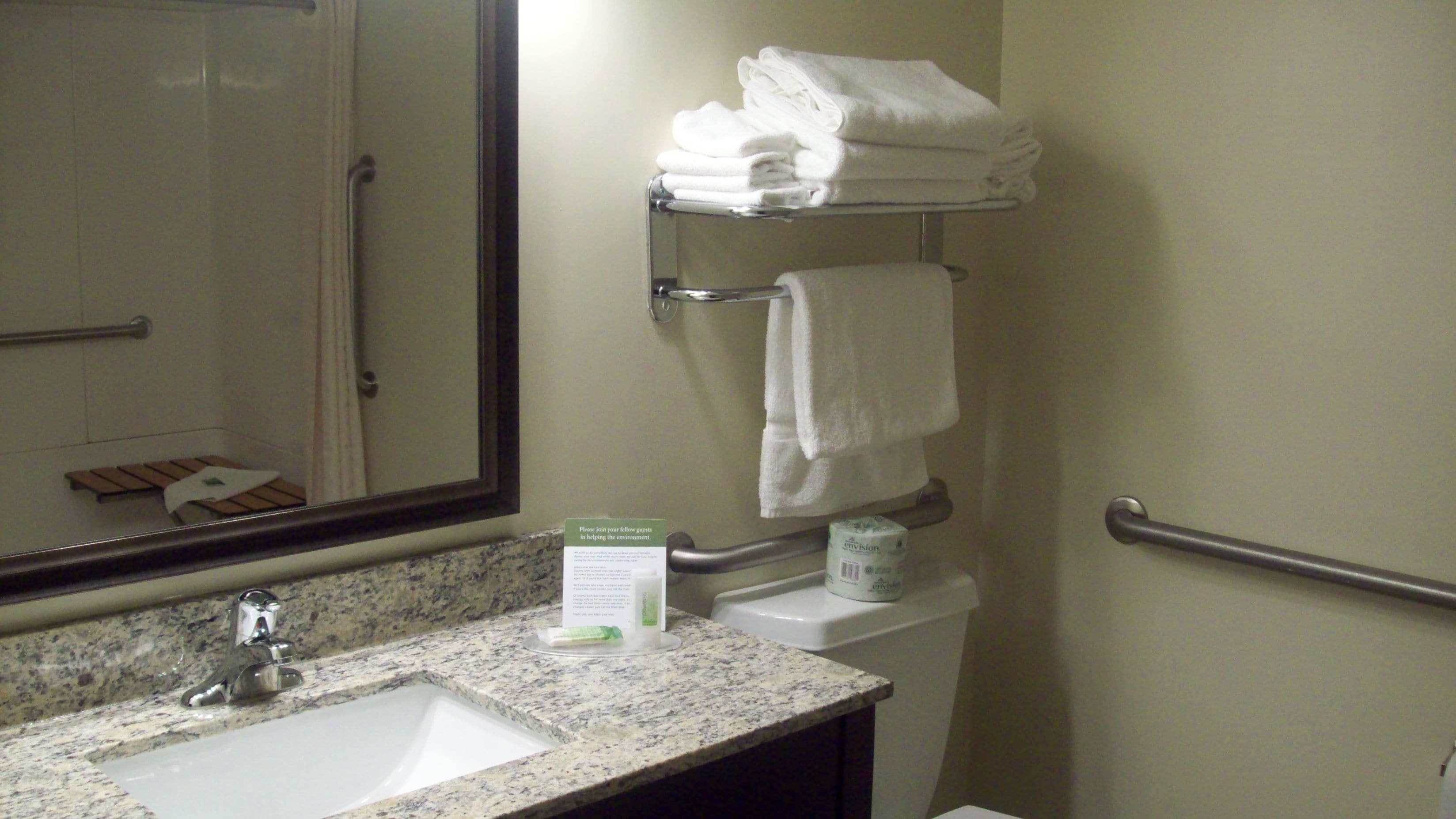 A bathroom with a sink, mirror, towel rack, and toilet.