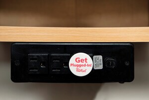 Un enchufe eléctrico negro con una tarjeta blanca que dice 'Get Plugged-In! RedRoof'.