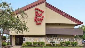 Un hôtel Red Roof Inn avec une façade en pierre, un toit rouge et un parking.