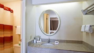 A bathroom with a toilet, sink, and mirror.