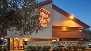 Un Red Roof Inn avec une façade en pierre, une entrée bien visible et un ciel dégagé.