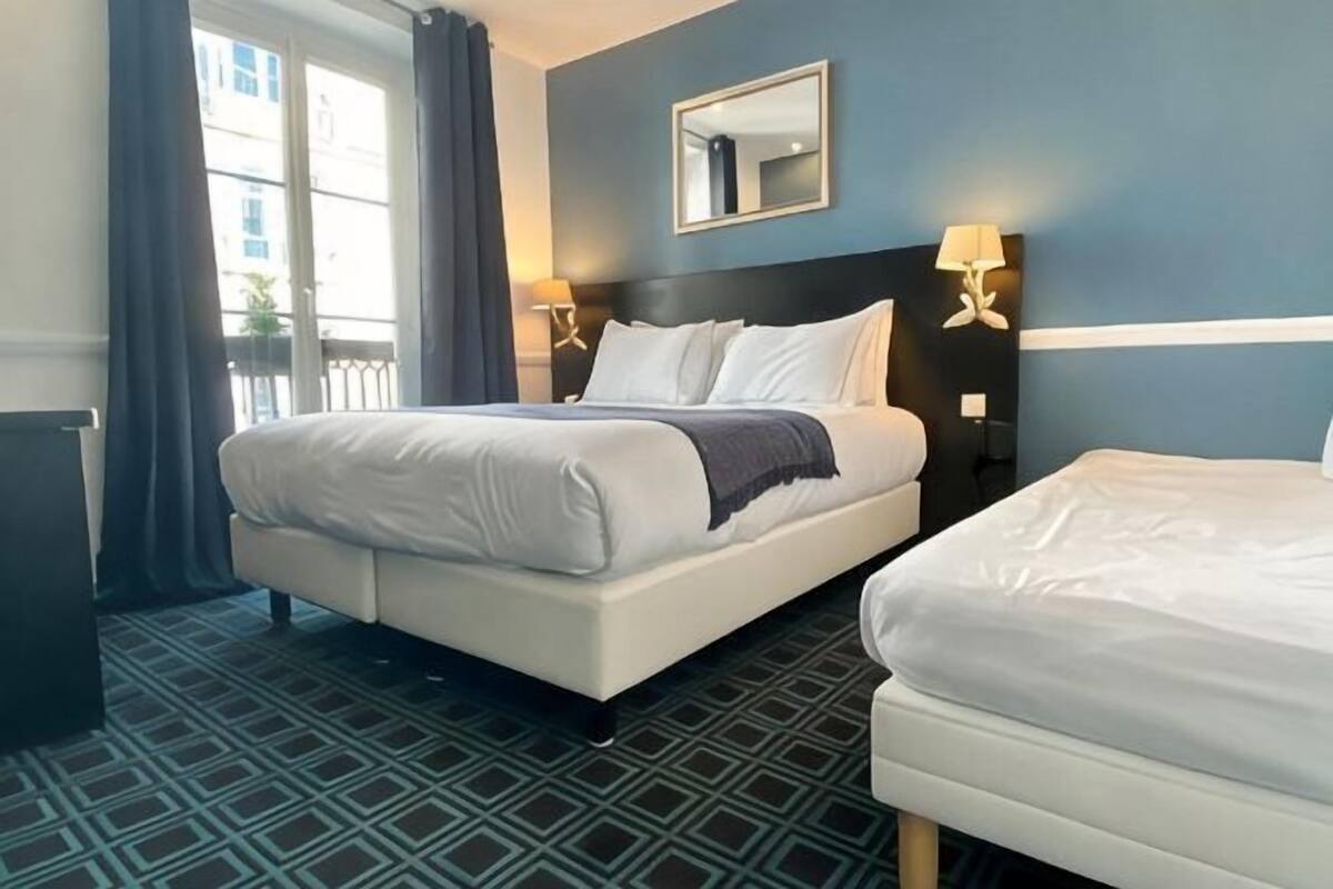 A hotel room with two beds, a large mirror, and a view of the outside.