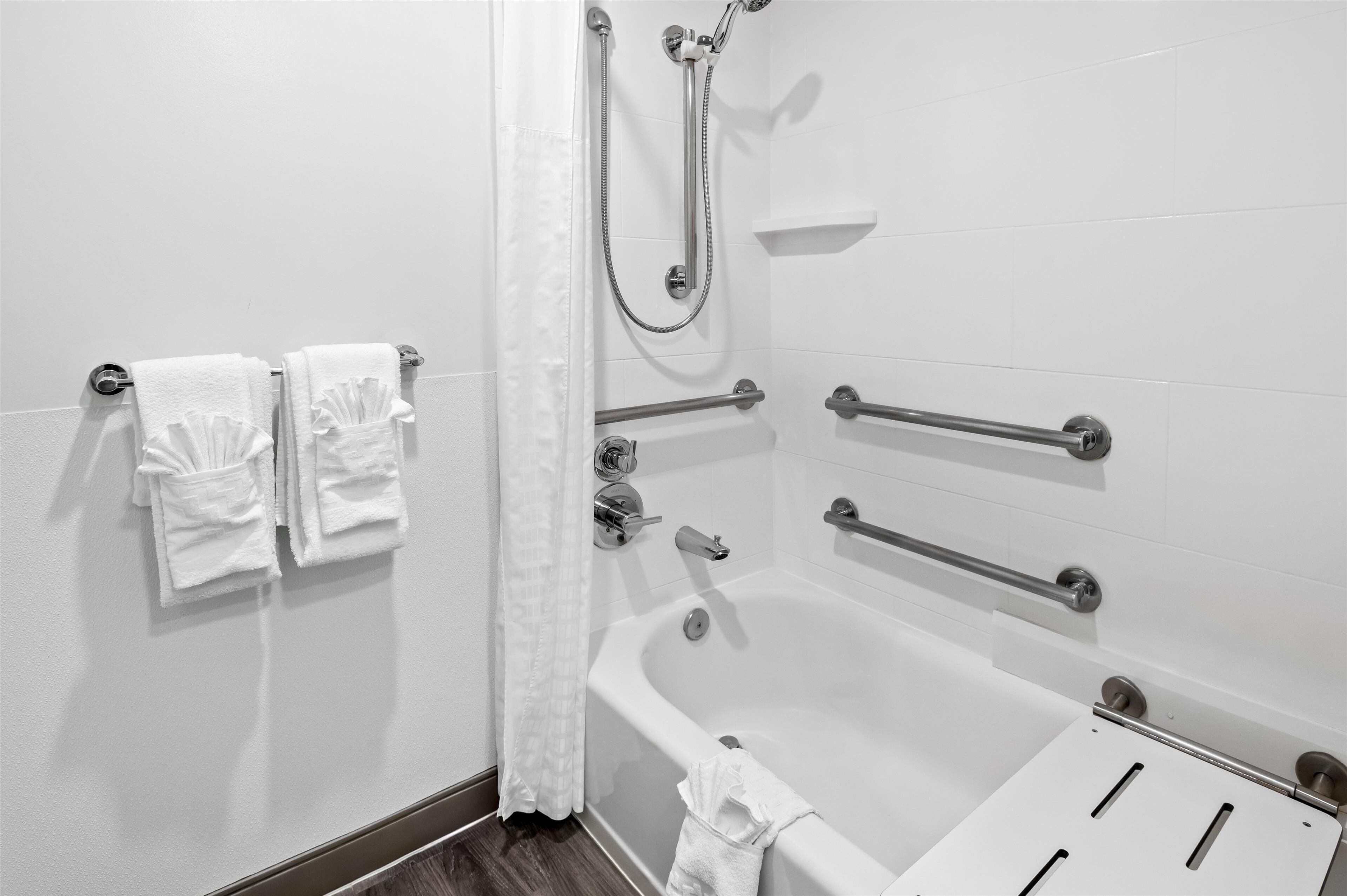 Ein Badezimmer mit Badewanne, Haltegriffen und Handtuchhalter.