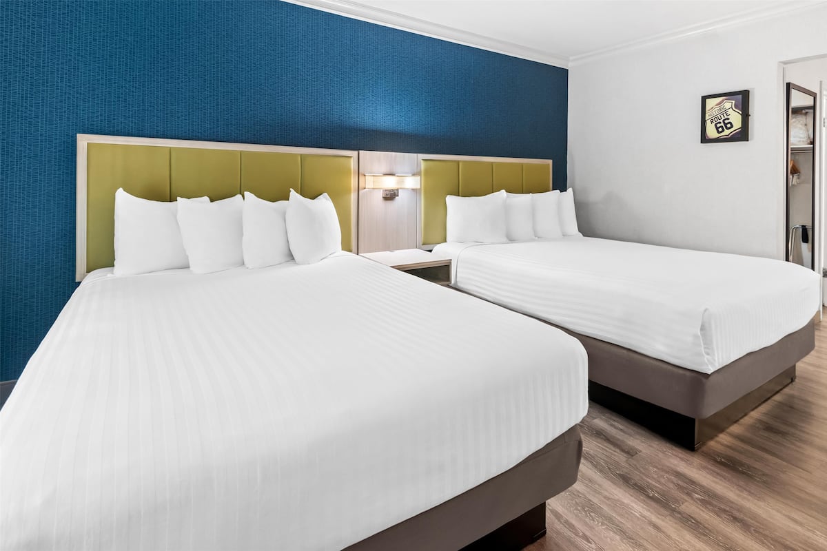 Ein Hotelzimmer mit zwei Betten, einer blauen Wand mit Struktur und einem gerahmten Schild an der Wand.