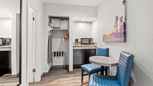 Quarto de hotel moderno com área de refeições, cozinha compacta e vista para a praia.