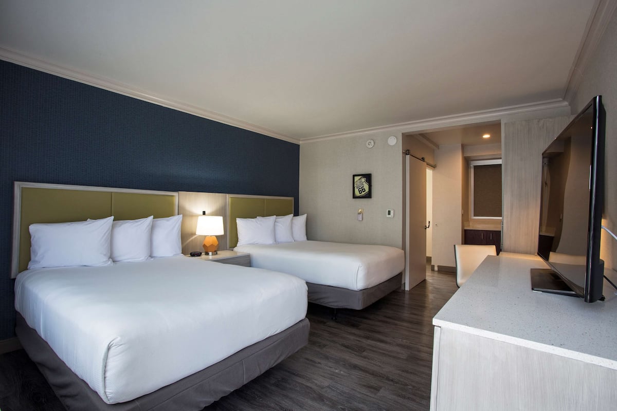 Ein Hotelzimmer mit zwei Betten, einem Schreibtisch und einem Fernseher.