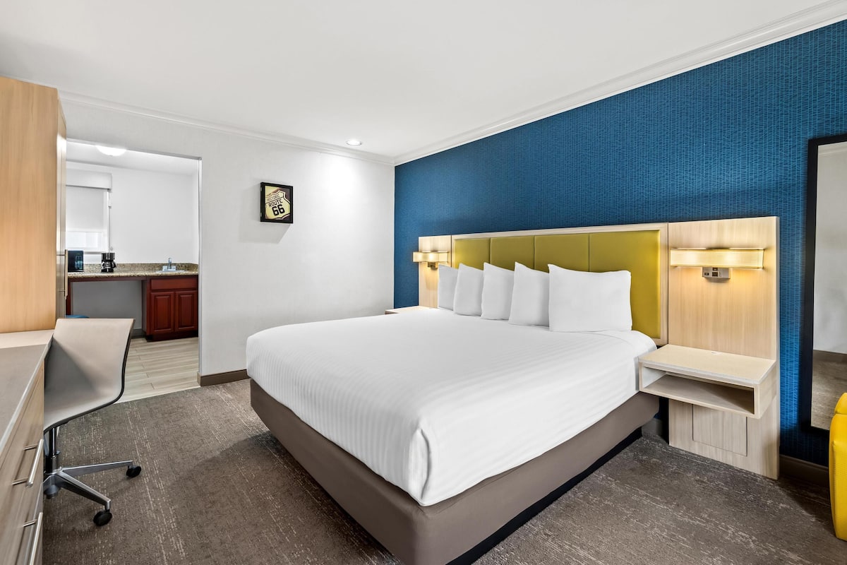 Ein modernes Hotelzimmer mit einem großen Bett, einem Schreibtisch und einer Küchenzeile.