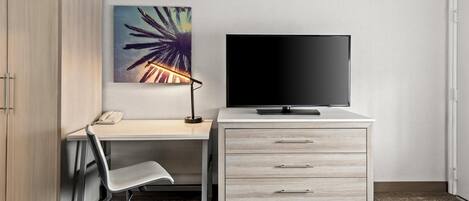 Una camera d'albergo con una scrivania, una sedia, una TV e un letto.