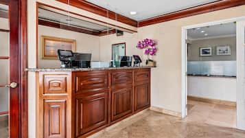 A reception desk with a coffee machine, a digital display, and a framed picture on the wall.