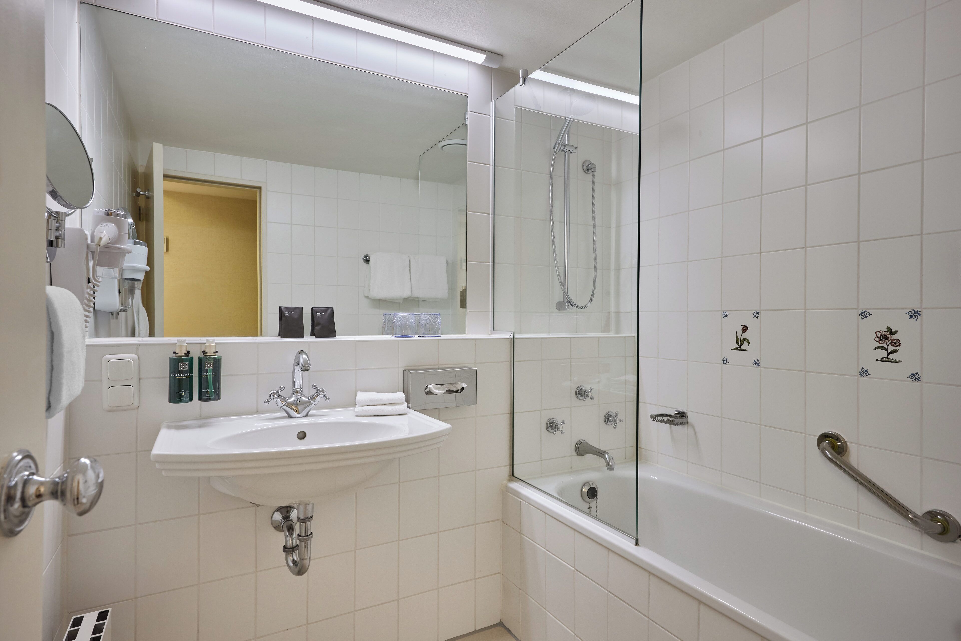 A modern bathroom with a white sink, a glass-enclosed shower, and a bathtub.