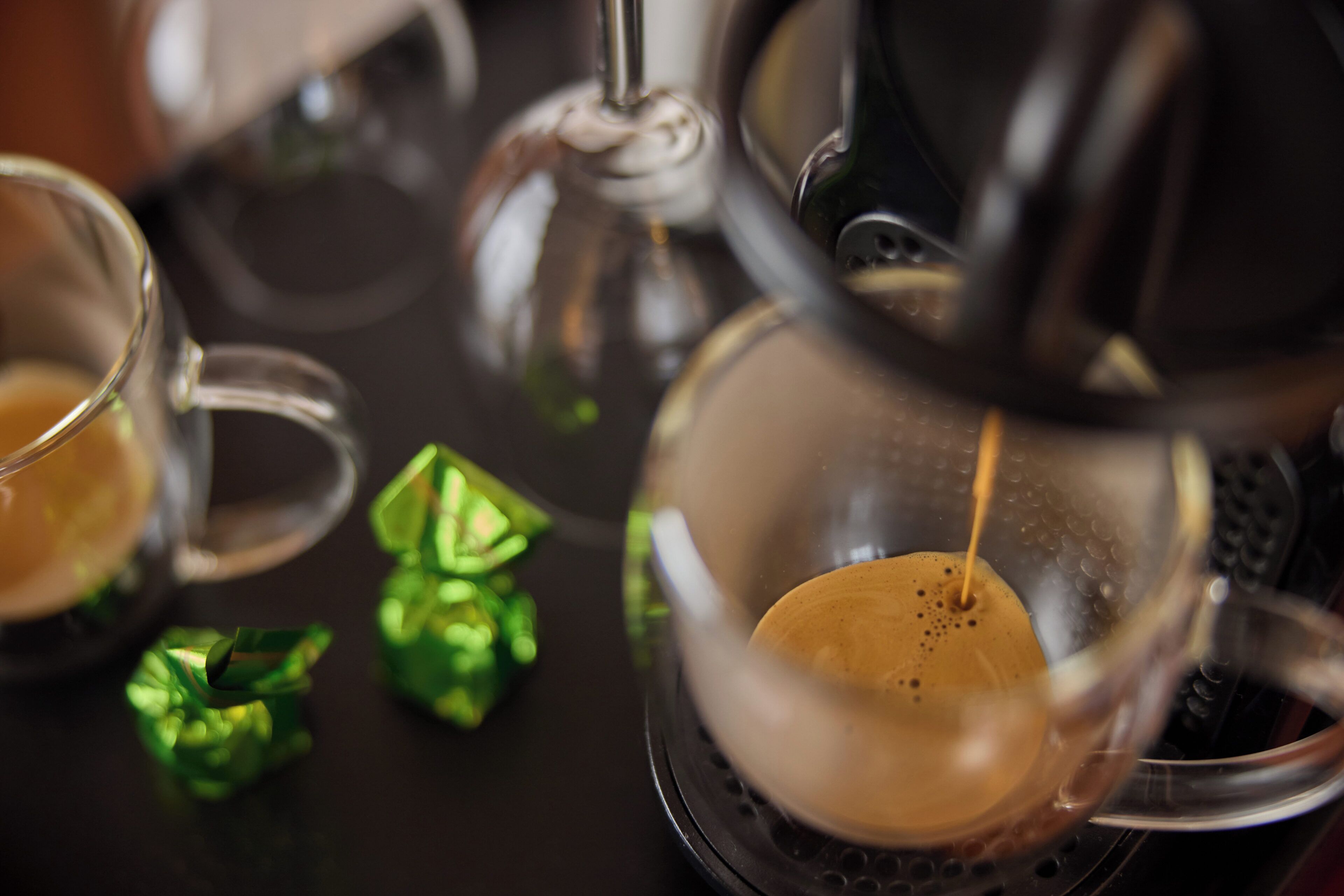 A coffee machine dispensing coffee into a glass cup.
