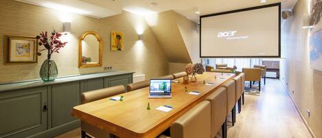 A conference room with a long table, chairs, a laptop, and a projector screen displaying 'acer Empowering People'.