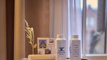 A tray with a towel, two bottles, and a decorative plant on a table in a hotel room.