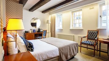 A hotel room with a bed, a desk, a chair, and a window.