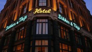 Un hôtel situé à l’angle d’une rue, dont la façade est ornée d’une enseigne lumineuse indiquant « Hôtel » et « Dikker & Thijs ».