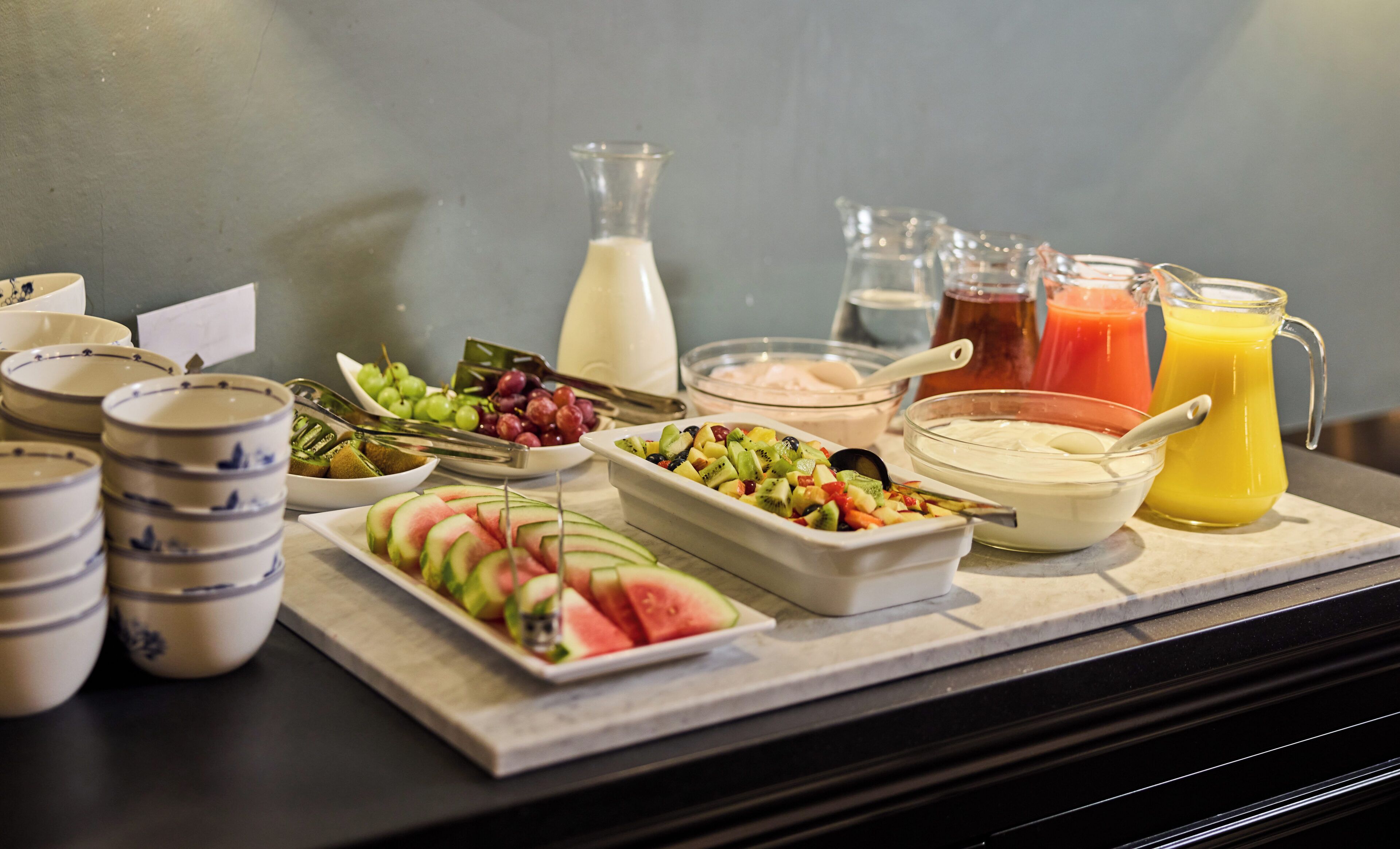 A breakfast buffet with various fruits, yogurt, and juices.