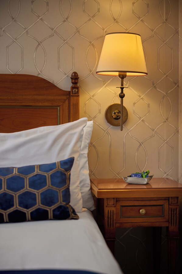 Una cama bien tendida con un cabecero de madera, una mesita de noche con una lámpara y un diseño decorativo en la pared.