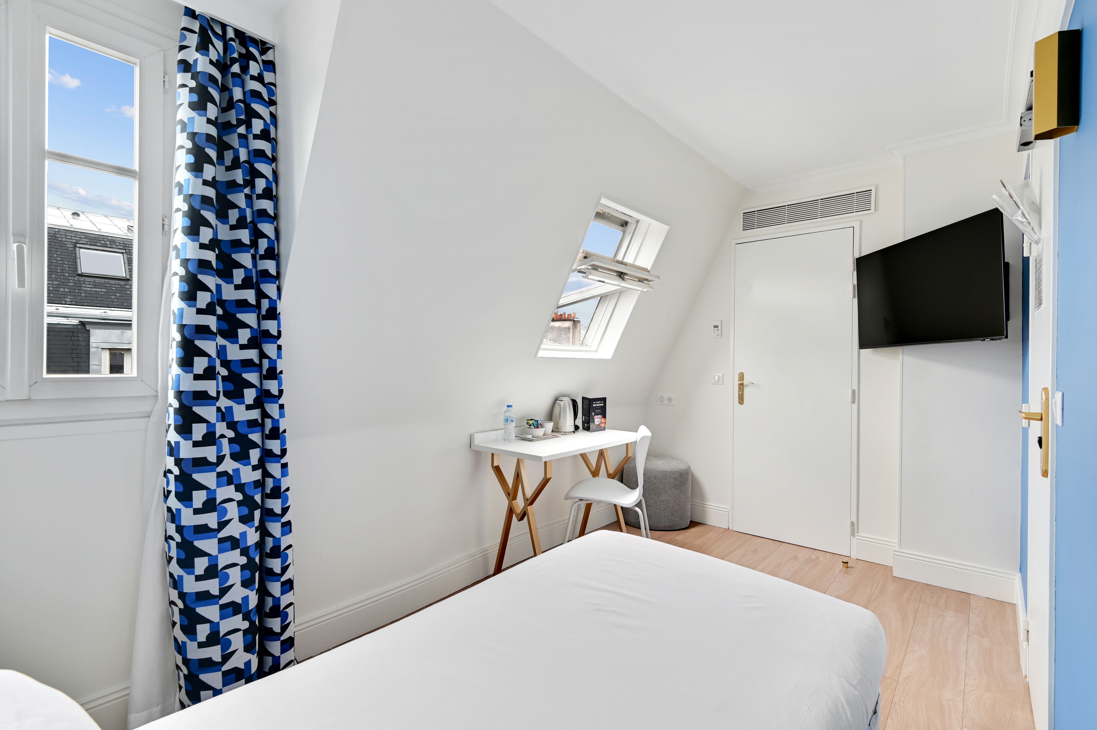 Un dormitorio con cama, escritorio, silla, televisor y ventana.