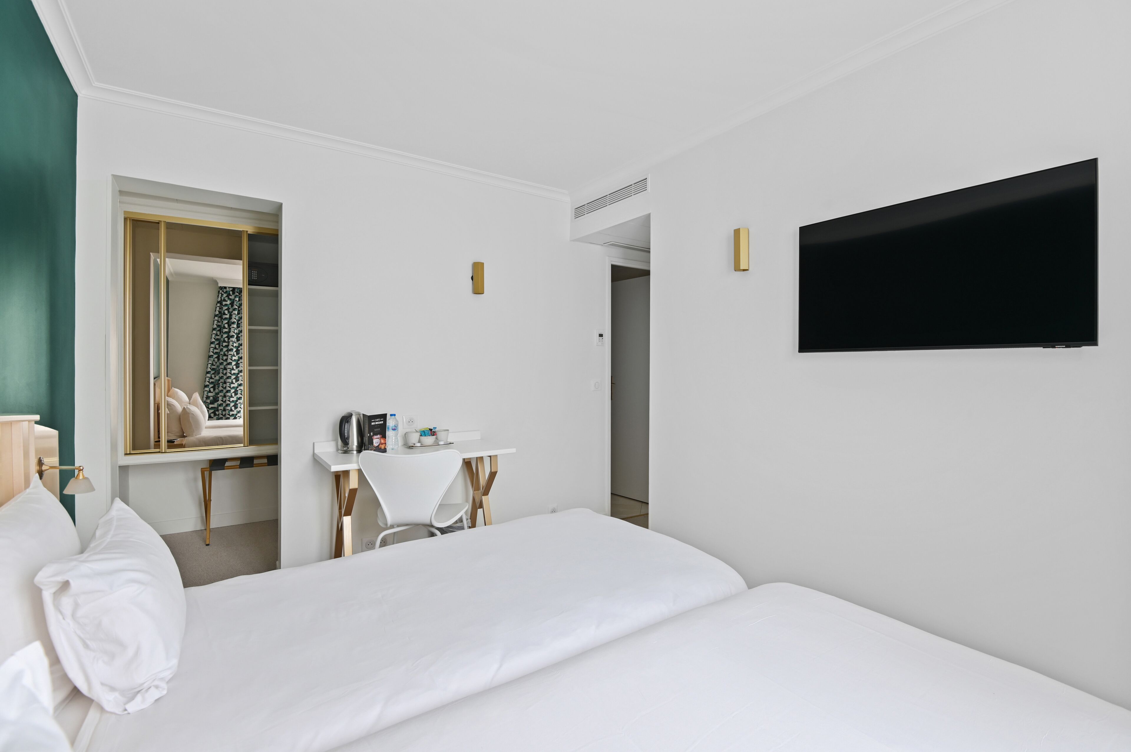 Ein Hotelzimmer mit Bett, Schreibtisch, Stuhl, Fernseher und Spiegel.