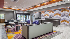 A lobby with seating areas, a reception desk, and a patterned wall.