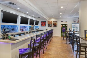 Una zona de bar con una barra larga, diversas opciones de asientos y decoración temática deportiva.