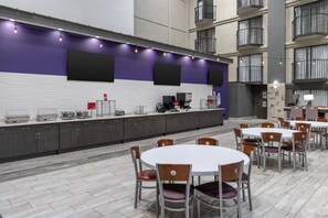 A modern indoor dining area with a long counter, multiple tables, and chairs. - Best Western Plus Clemson Hotel & Conference Center (Clemson)