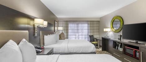 Quarto de hotel com duas camas, televisão, micro-ondas e secretária com abajur.