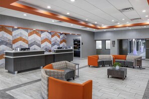 A modern reception area with a check-in counter, seating area, and a patterned wall. - Best Western Plus Clemson Hotel & Conference Center (Clemson)