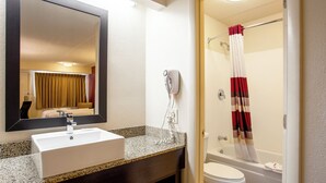 A bathroom with a sink, mirror, hairdryer, and a shower curtain.