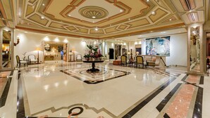 A spacious lobby with a polished marble floor, a central floral arrangement, and a large painting on the wall. - Olissippo Lapa Palace – The Leading Hotels of the World (Lisbon)