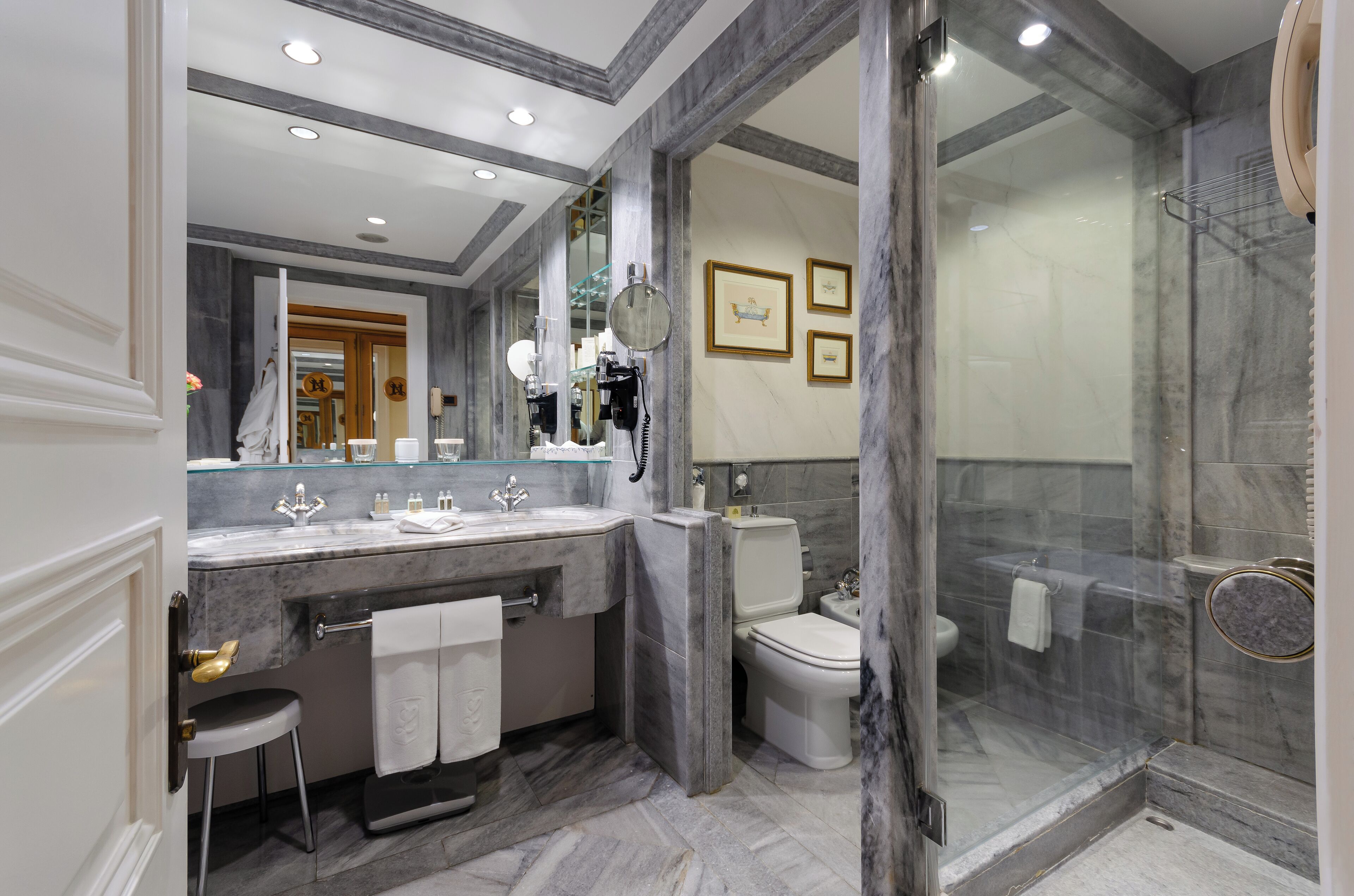 Een moderne badkamer met een marmeren wastafelmeubel, een douchecabine met glazen wanden en een toilet.