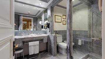Een moderne badkamer met een marmeren wastafelmeubel, een douchecabine met glazen wanden en een toilet.
