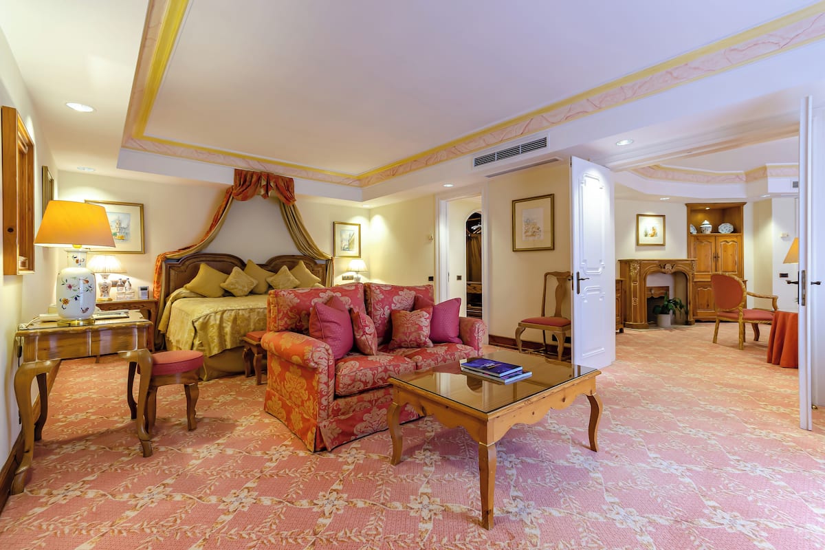 A hotel room with a bed, a sofa, a coffee table, and a desk.