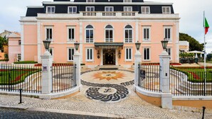 A large, two-story building with a symmetrical facade, a central entrance, and a decorative circular mosaic in the courtyard. - Olissippo Lapa Palace – The Leading Hotels of the World (Lisbon)