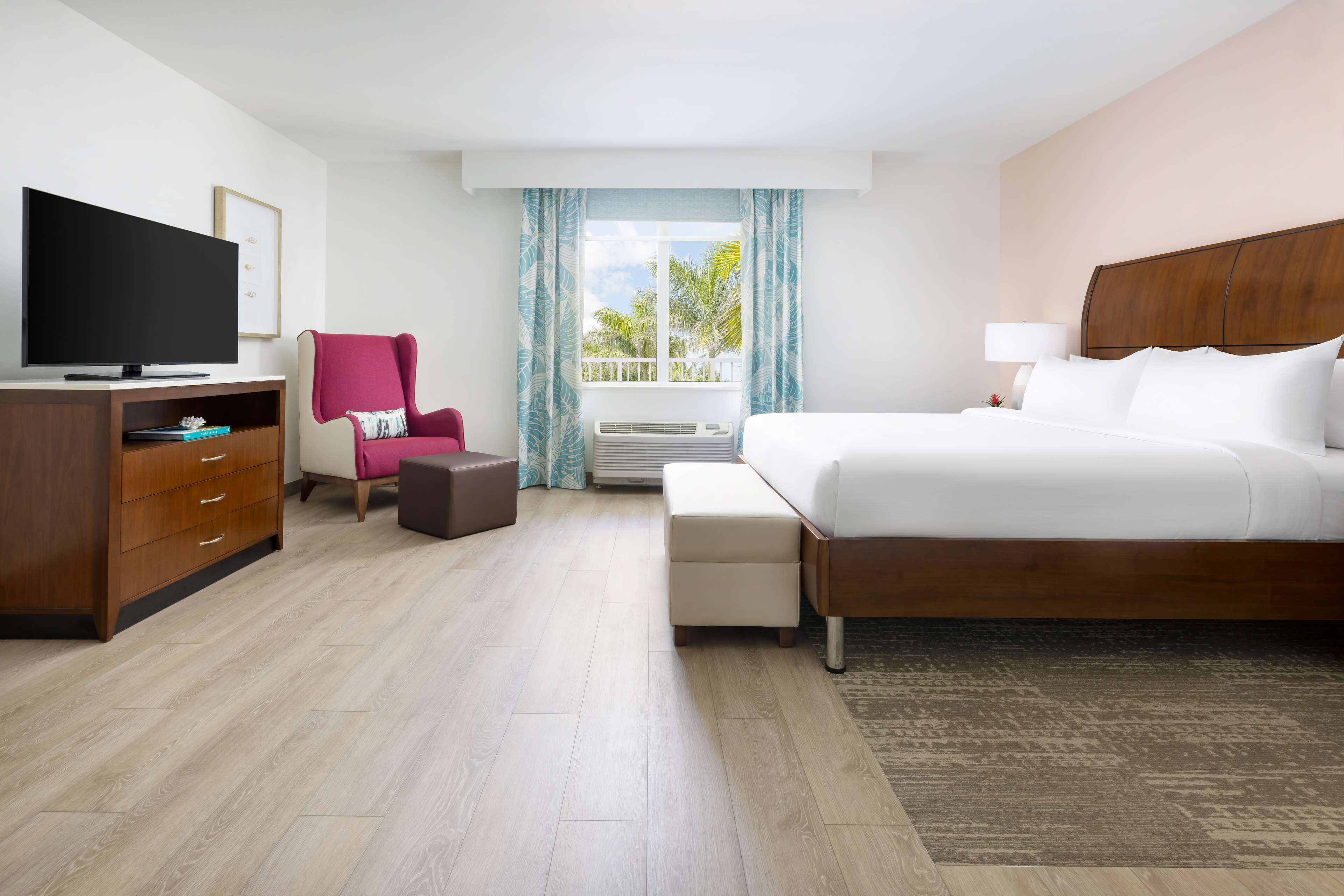 Una habitación de hotel con una cama grande, un televisor, un escritorio y una silla.