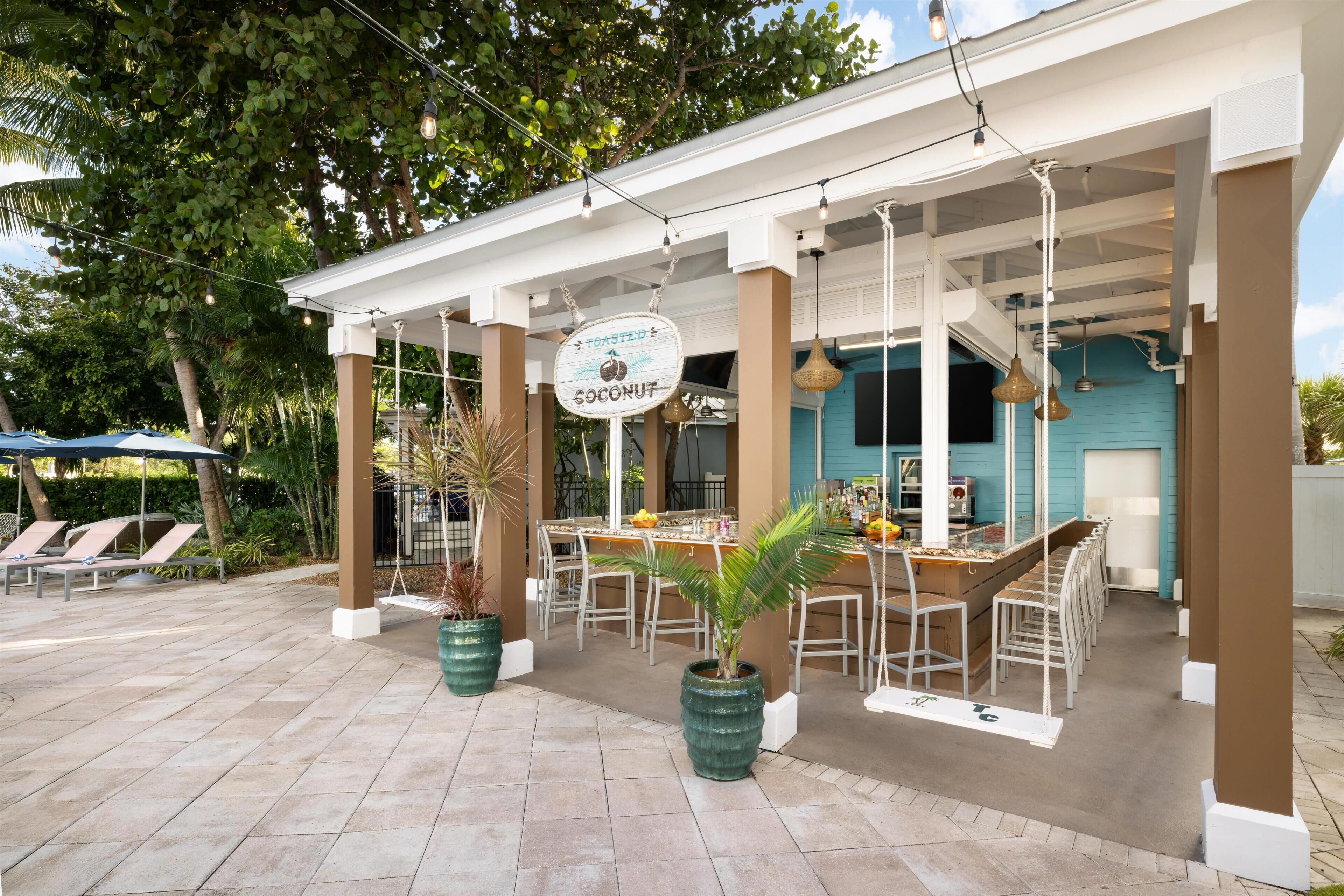 An outdoor seating area with a bar, lounge chairs, and potted plants.