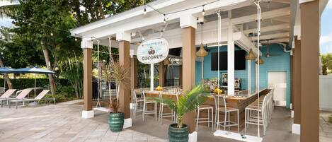 An outdoor seating area with a bar, lounge chairs, and potted plants.