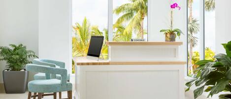 A reception desk with a view of palm trees through large windows.