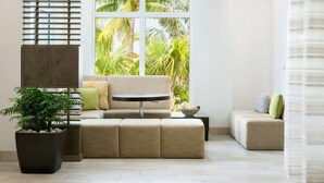 A modern living room with a sectional sofa, a small round table, and a potted plant. - Hilton Garden Inn Key West / The Keys Collection (Key West)
