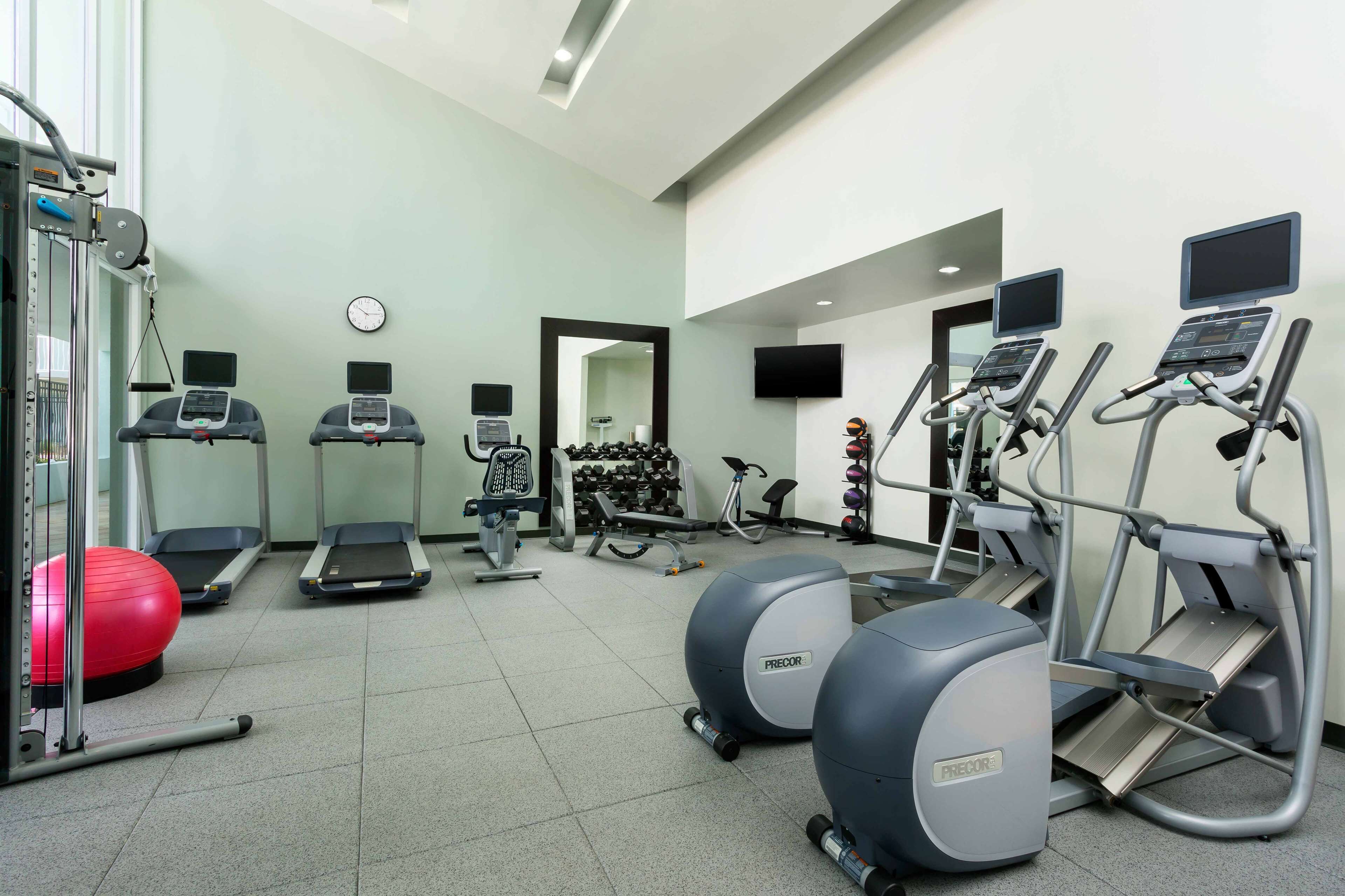 A gym with treadmills, elliptical machines, and free weights.