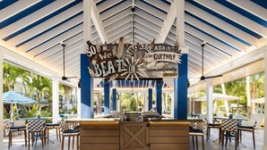 A covered outdoor seating area with a central bar, patterned chairs, and a decorative sign. - Hilton Garden Inn Key West / The Keys Collection (Key West)