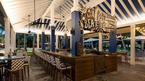 A bar area with a wooden counter, bar stools, and a sign that reads 'So we BEATON.' - Hilton Garden Inn Key West / The Keys Collection (Key West)