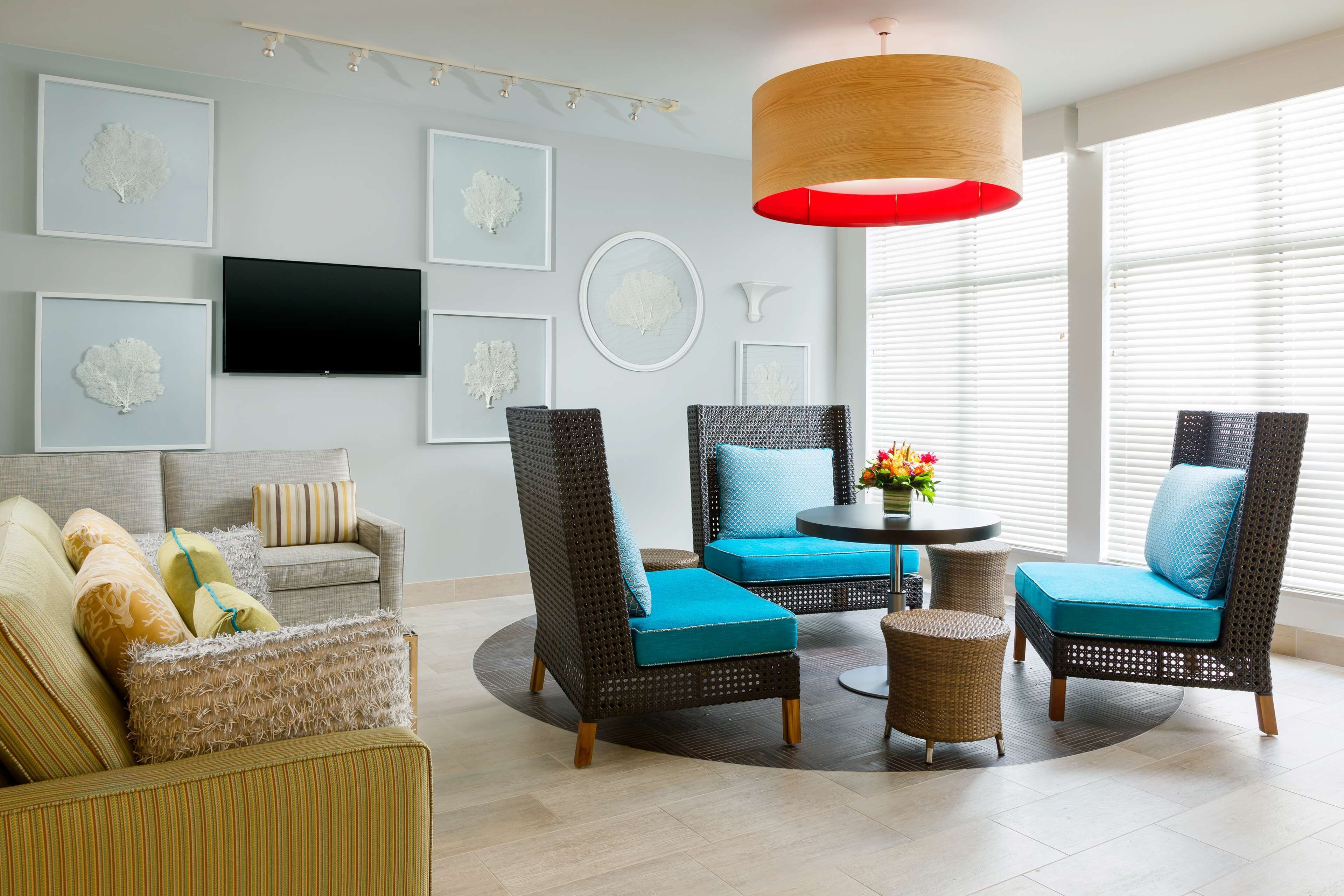 A modern living room with wicker furniture, a flat-screen TV, and artwork on the walls.